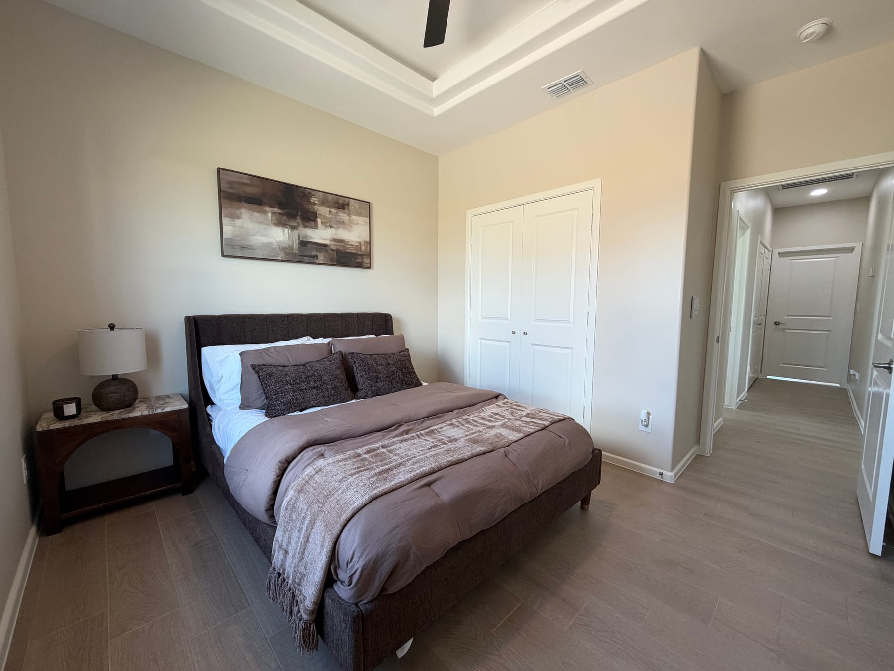 The same bedroom from the window side, with its double closet doors and the hallway beyond